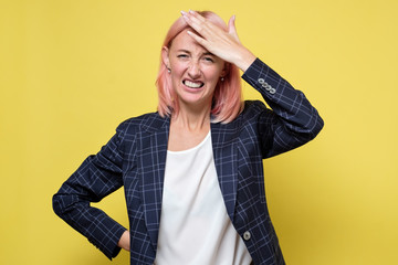 Dissatisfied young woman regrets about wrong decision, keeps hand on forehead.