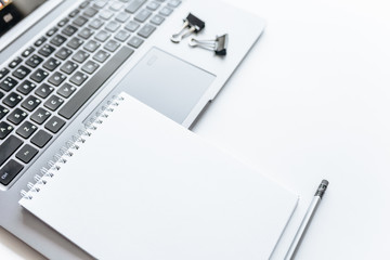 Notebook, laptop, stickers, paper clips in the workspace on the table in the office.