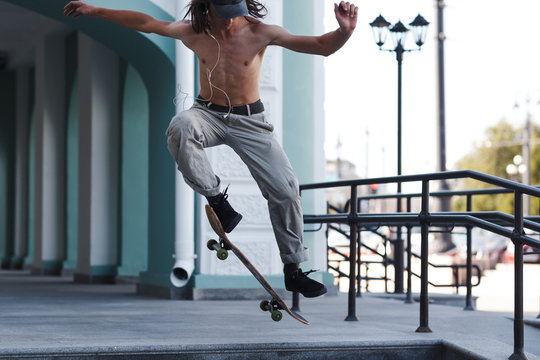 Young Boy Riding Trick On Skateboard In City.