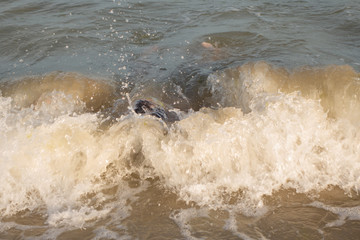 Obraz premium A 10-year-old boy is swimming and having fun in the sea near the shore in green swimming goggles.