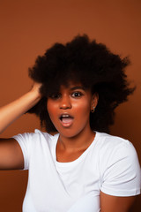 pretty young african american woman with curly hair posing cheerful gesturing on brown background, lifestyle people concept