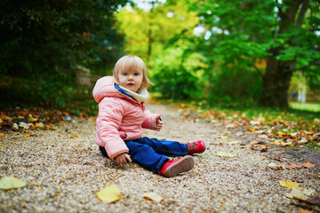 Adorable cheerful toddler girl in autumn park in Paris