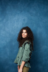 young pretty woman with curly brunette hair posing cheerful on blue background, lifestyle people concept