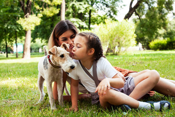 young pretty caucasian mother walking with little cute daughter and dog fox terrier, lifestyle people concept