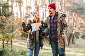 Travel couple with map, compass and backpack in the forest. Freedom and active travel concept.