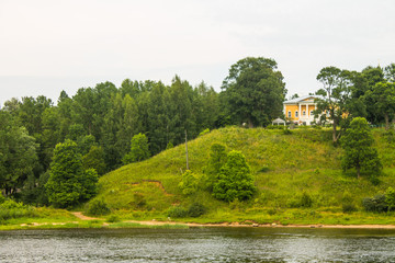 Fototapeta na wymiar Summer landscape-a beautiful building on a hill and green trees on the banks of the Volga river in Russia on a cloudy day and a space to copy