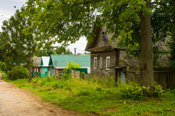 a street with old wooden Russian huts and green trees on a summer day and space for copying in Kalyazin Russia