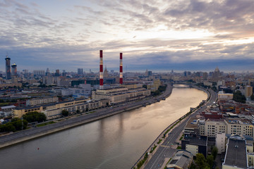 a factory on the river embankment with large striped pipes