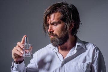 Bearded man holds bottle of perfume. Cosmetics. Scent cologne bottle. Masculine perfume. Man perfume, fragrance. Perfume or cologne bottle and perfumery.