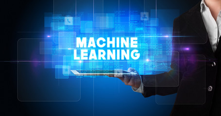 Young business person working on tablet and shows the inscription: MACHINE LEARNING