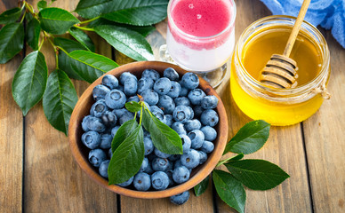 Ripe, fresh blueberries in a wooden bowl on an old background.