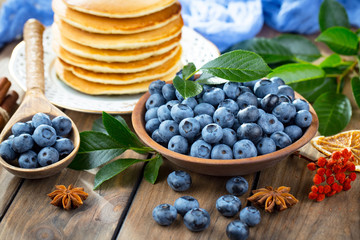 Blueberries in a plate and pancakes, on an old background.