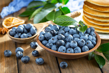 Blueberries in a plate and pancakes, on an old background.