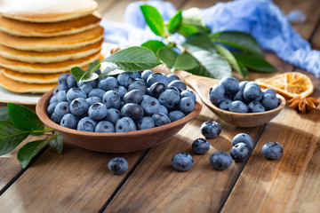 Blueberries in a plate and pancakes, on an old background.