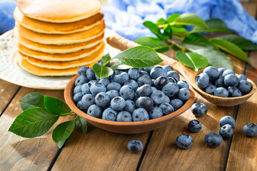 Blueberries in a plate and pancakes, on an old background.
