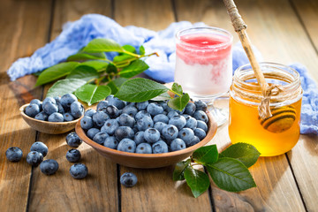 Ripe, fresh blueberries in a wooden bowl on an old background.