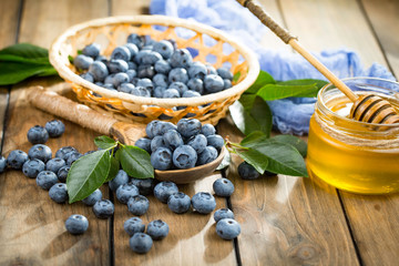 Ripe, fresh blueberries in a wooden bowl on an old background.