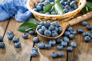 Ripe, fresh blueberries in a wooden bowl on an old background.