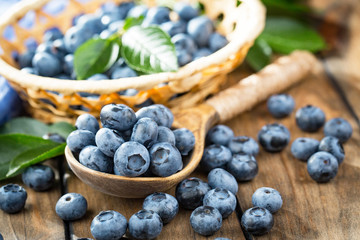 Ripe, fresh blueberries in a wooden bowl on an old background.