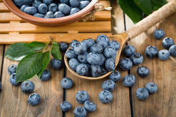 Ripe, fresh blueberries in a wooden bowl on an old background.