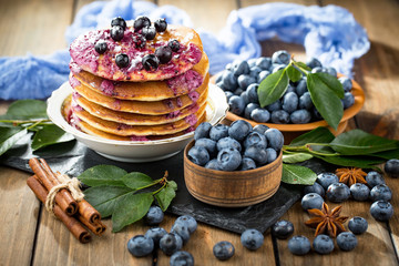 Obraz na płótnie Canvas Blueberries in a plate and pancakes, on an old background.
