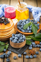 Blueberries in a plate and pancakes, on an old background.
