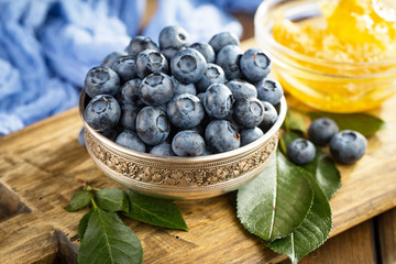 Blueberries in a plate and pancakes, on an old background.