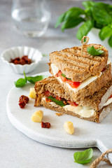 Delicious toast with white asparagus, tomatoes, mozzarella, sun-dried tomatoes and basil on white marble board. Healthy food concept with copy space.