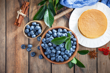 Blueberries in a plate and pancakes, on an old background.