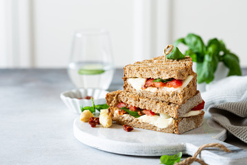 Delicious toast with white asparagus, tomatoes, mozzarella, sun-dried tomatoes and basil on white marble board. Healthy food concept with copy space.