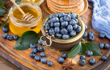Ripe, fresh blueberries in a wooden bowl on an old background.