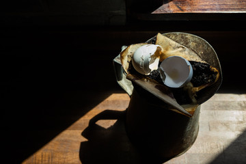 old broken eggshells and coffee grounds in rusty can in the sun and shadows ready for compost bin