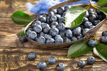 Ripe, fresh blueberries in a wooden bowl on an old background.