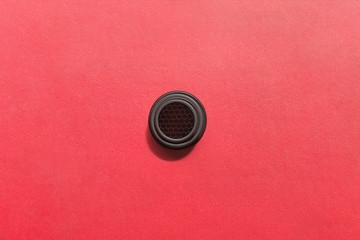 A metal honeycomb circle on a  textured red background.