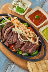 Beef Fajitas with colorful bell peppers in pan and sauces