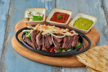 Beef Fajitas with colorful bell peppers in pan and sauces