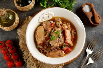 Stewed chicken legs in tomato sauce with onions, garlic and parsley. Top view. 