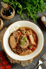 Stewed chicken legs in tomato sauce with onions, garlic and parsley. Top view. 