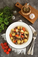 Baked chicken hearts with potatoes, onions, carrots and garlic in the oven.