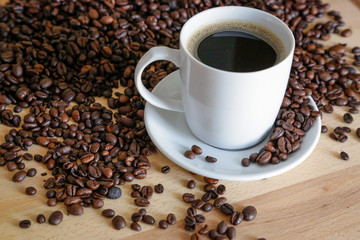  A cup of black coffee with coffee grains, natural light on wooden table