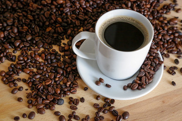  A cup of black coffee with coffee grains, natural light on wooden table