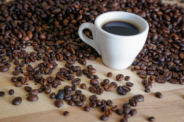 A cup of black coffee with coffee grains, natural light on wooden table