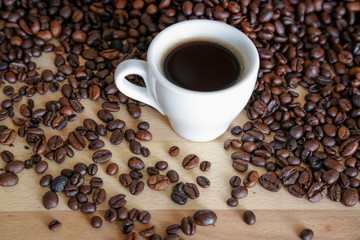  A cup of black coffee with coffee grains, natural light on wooden table