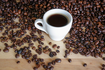  A cup of black coffee with coffee grains, natural light on wooden table