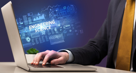 Businessman working on laptop with ENGINEERING SCIENCE inscription, cyber technology concept
