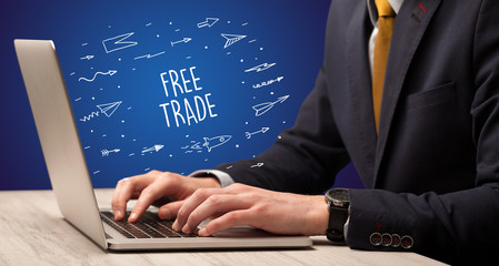 Fototapeta na wymiar Businessman working on laptop with FREE TRADE inscription, online shopping concept