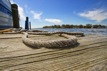 Obraz premium Dock Line Laying on the Boat Dock Next to a Boat on a Sunny Day