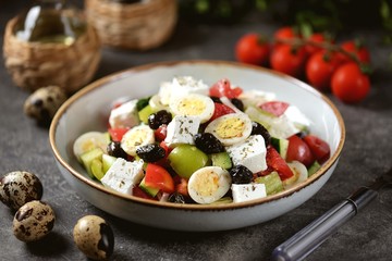 Greek salad with quail eggs. Salad with peppers, tomatoes, cucumbers, feta, oregano, olives, onions, olive oil and lemon juice.