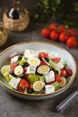 Greek salad with quail eggs. Salad with peppers, tomatoes, cucumbers, feta, oregano, olives, onions, olive oil and lemon juice.
