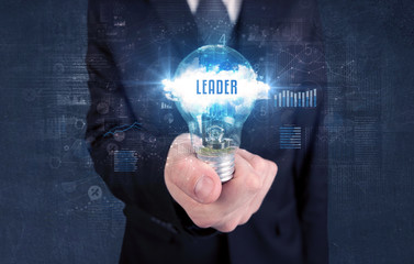 Businessman holding a light bulb with LEADER inscription, new business concept